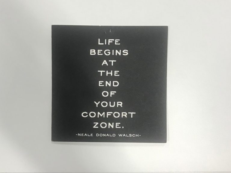 a sign which reads "Life begins at the end of your comfort zone"